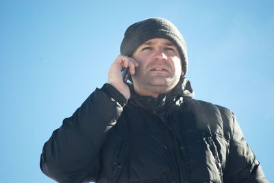 Portrait of young man using smart phone against sky