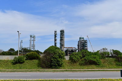 Road by factory against sky