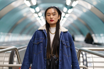 Asian girl street fashion look. stylish female wearing leather beret on escalator ride to subway