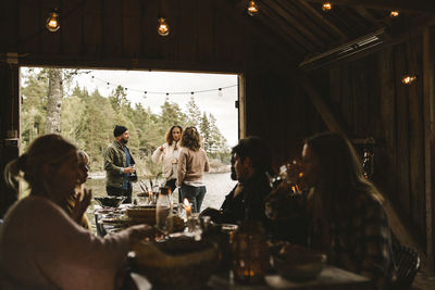 Male and female friends talking outside cottage during social gathering