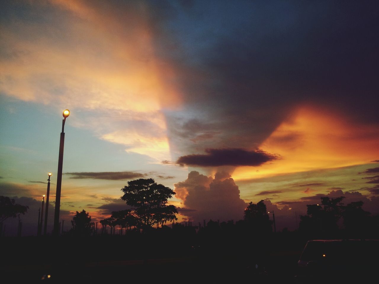 sunset, silhouette, sky, tree, scenics, beauty in nature, cloud - sky, orange color, tranquility, tranquil scene, street light, nature, dramatic sky, idyllic, cloud, cloudy, dusk, outdoors, low angle view, landscape