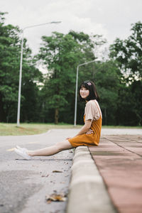 Side view of young woman sitting on road