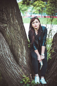 Young woman standing on tree trunk