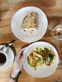 Directly above shot of hand holding breakfast served on table