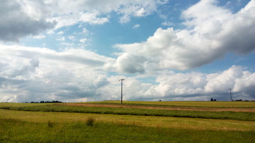 Scenic view of grassy field against cloudy sky