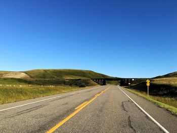 Road by landscape against clear blue sky