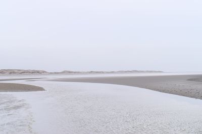 Scenic view of beach against clear sky during winter