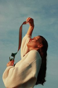 Midsection of woman holding film roll against sky