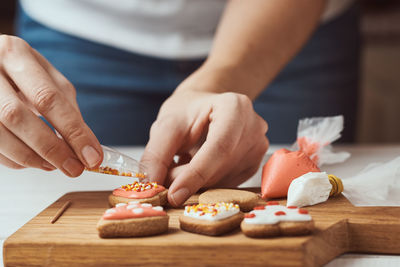 Decorating gingerbread cookies with icing. woman hands decorate cookies in shape of heart, closeup