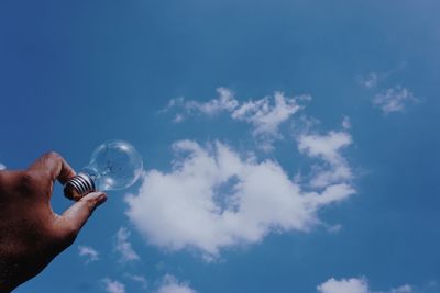 Low angle view of person hand against blue sky