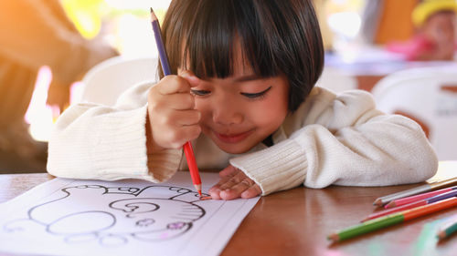 Girl painting in book on table