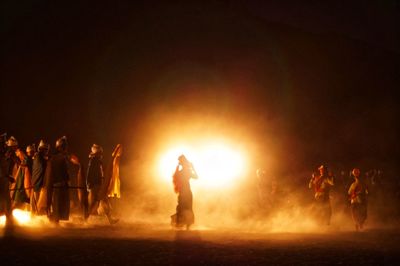 People wearing traditional clothing while dancing in event at night