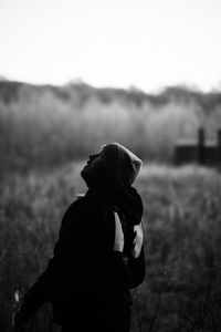 Man looking up while standing on field against sky