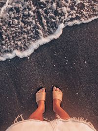 Low section of woman standing at beach