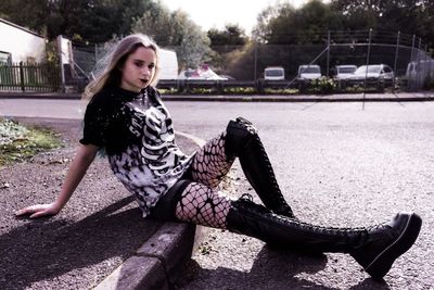 Young woman sitting on sidewalk