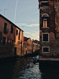 Canal amidst buildings in city against sky