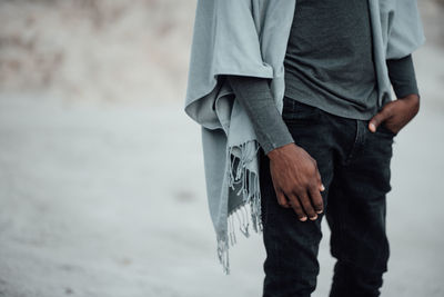 Midsection of man holding umbrella standing at shore