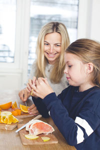 Mother and daughter playing with fruits at home