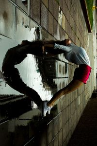 Side view of man lying on wall