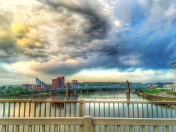 Bridge over river against cloudy sky