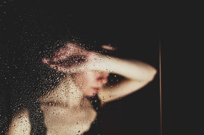 Portrait of woman seen through wet glass