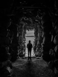 Rear view of silhouette woman standing in cave