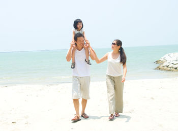 Full length of friends standing on beach