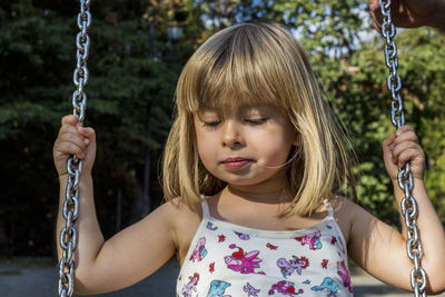 Close-up of cute girl on swing at playground