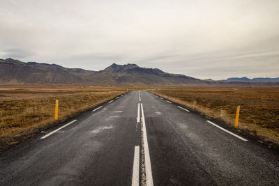 Road leading towards mountains against sky