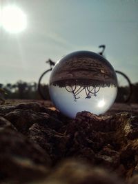 Close-up of crystal ball on land against sky