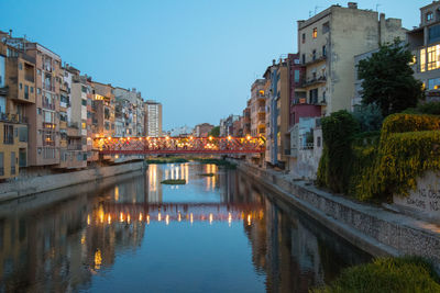 Bridge over river amidst buildings against sky in city