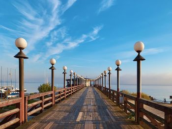 Street light on footpath by sea against sky