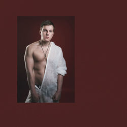 Portrait of young man standing against red wall