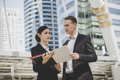 Low angle view of business people discussing while standing against building