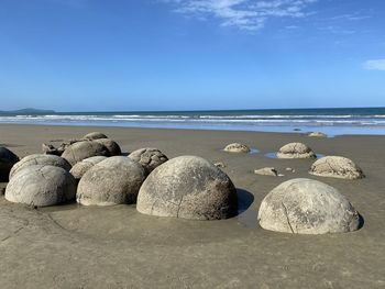 Rocks on beach against blue sky