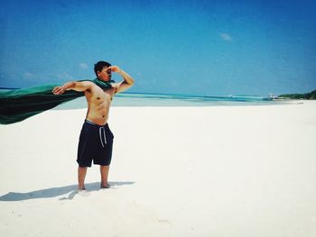 Full length of shirtless man standing on beach