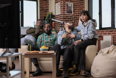 Friends using laptop while sitting on sofa at home