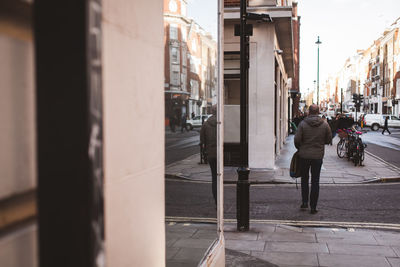 Rear view of man walking on sidewalk