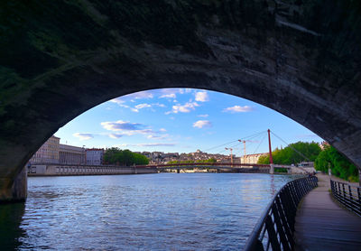 Bridge over river in city against sky