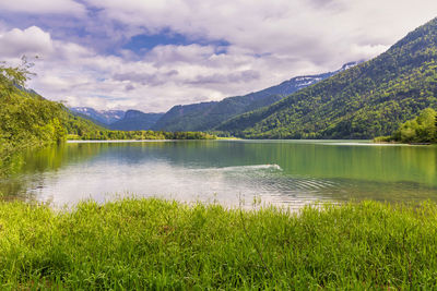 Scenic view of lake by mountains against sky