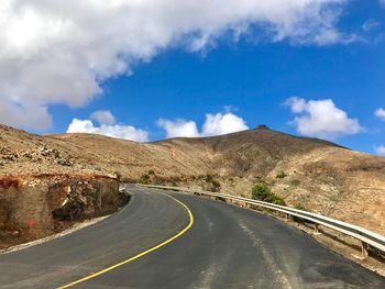 Road leading towards mountains against sky