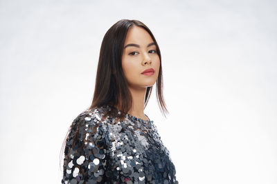 Portrait of young woman standing against white background