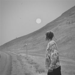 Rear view of man standing on field against sky