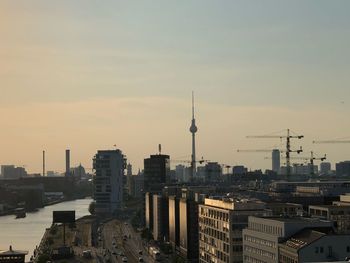 Modern buildings in city against sky during sunset