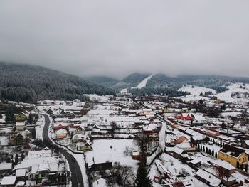 Aerial view of snow covered buildings in city against sky