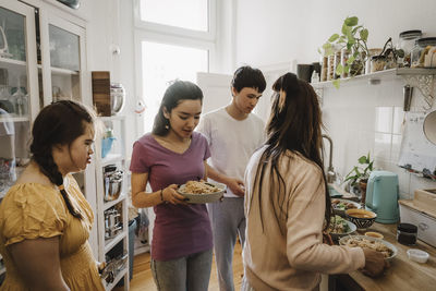 Children helping mother while preparing food in kitchen at home