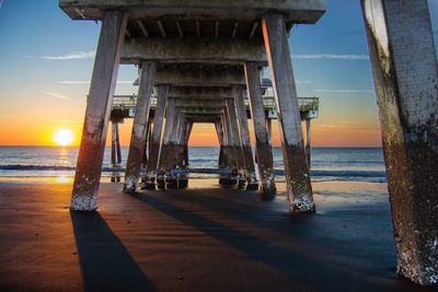 Below view of jetty on shore at beach during sunset