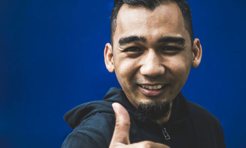 Portrait of smiling young man against blue sky