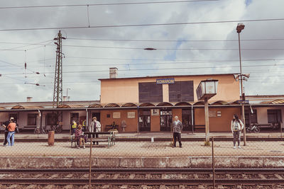 People on railroad tracks against sky