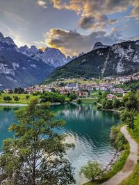 Scenic view of lake by buildings and mountains against sky